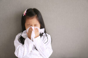 Female child blowing nose into a tissue