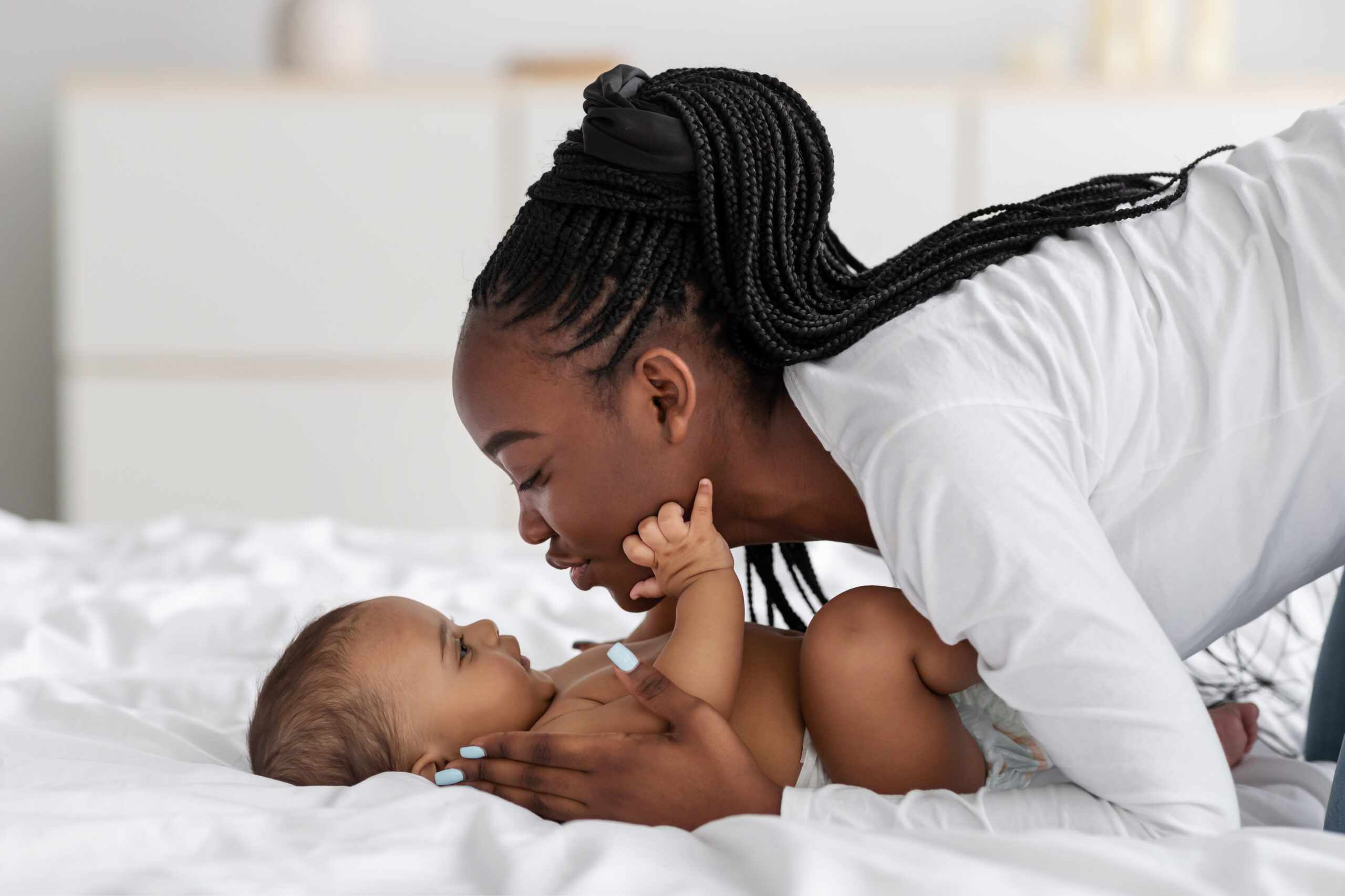 Black,Mom,Playing,In,Bed,With,Her,Infant,,Kissing,Baby