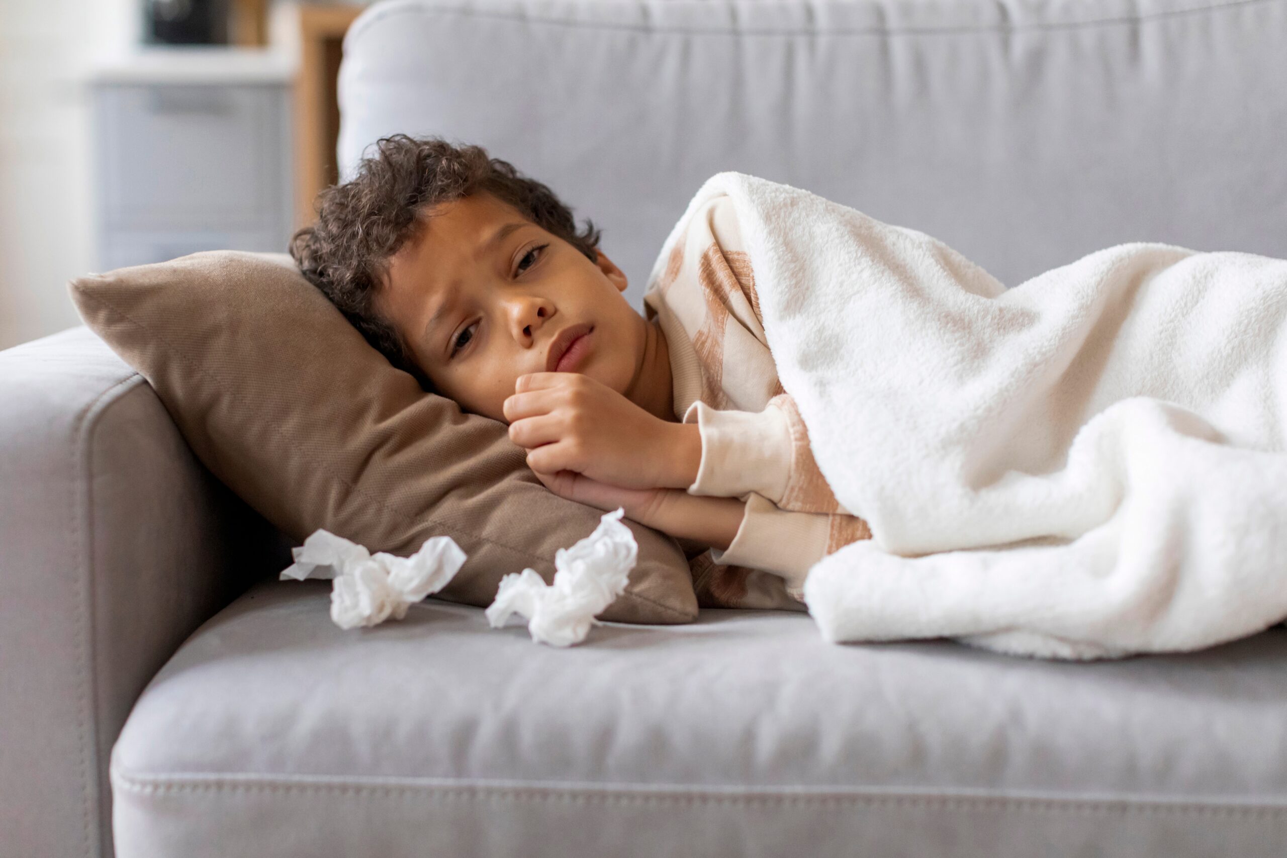 child resting on couch – flu symptoms in children