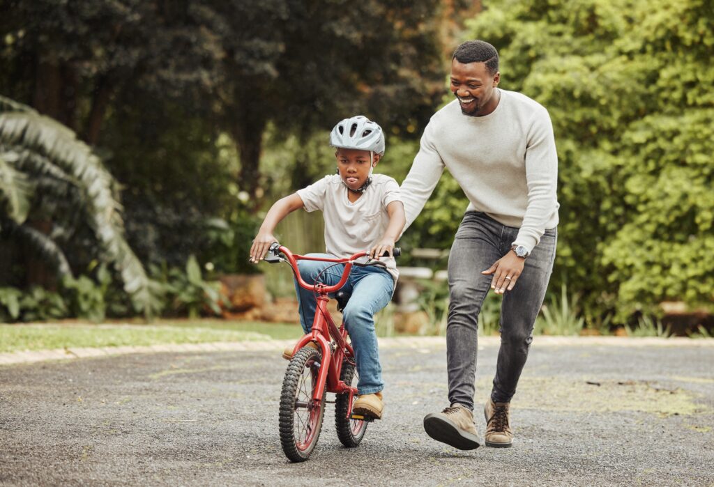 parent teaching child to ride a bike, practicing bike safety for kids
