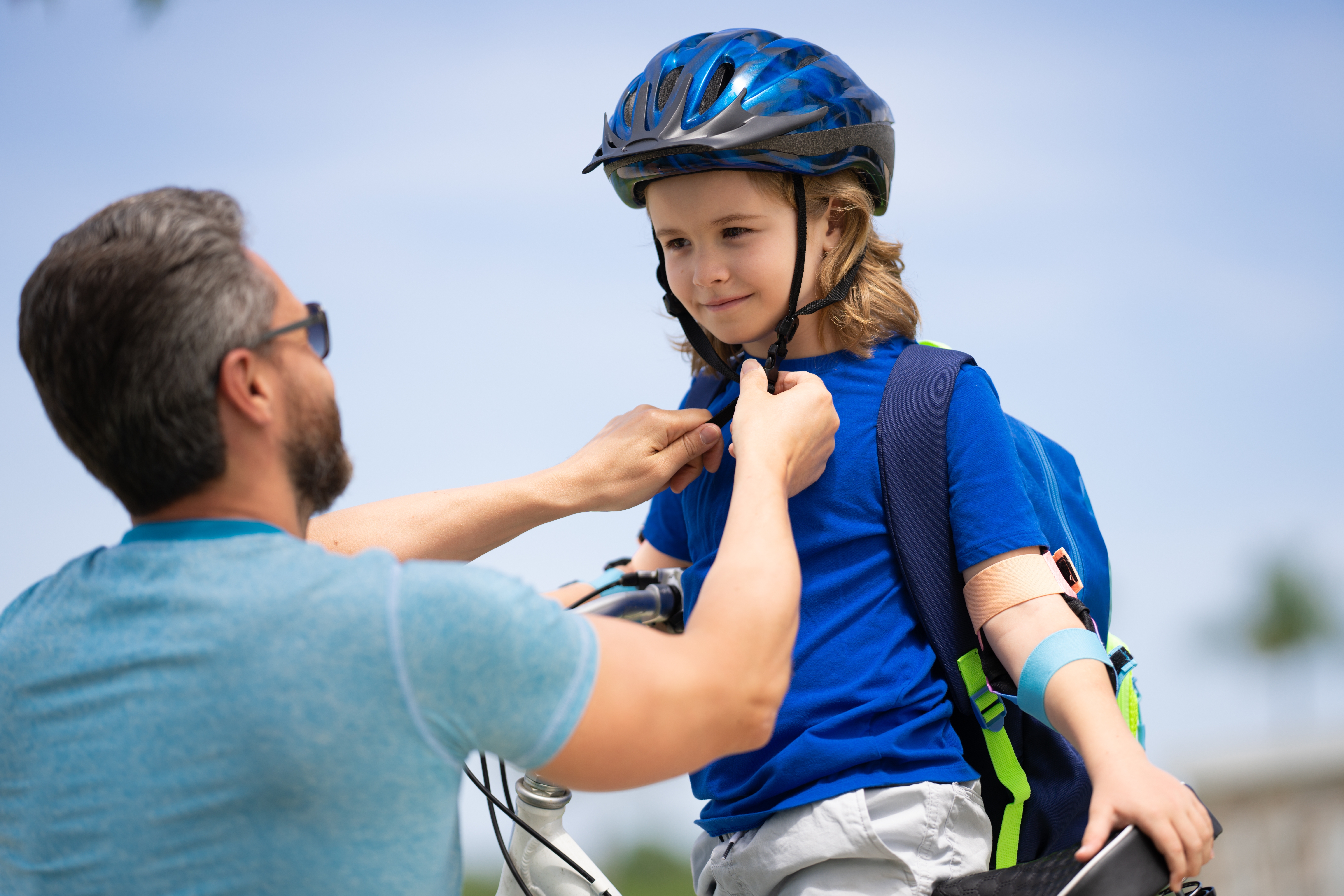 parent helping child fasten helmet, practicing bike safety for kids
